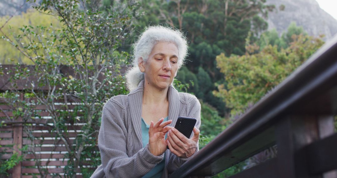 Senior Woman Using Smartphone Outdoors In Garden Setting - Free Images, Stock Photos and Pictures on Pikwizard.com