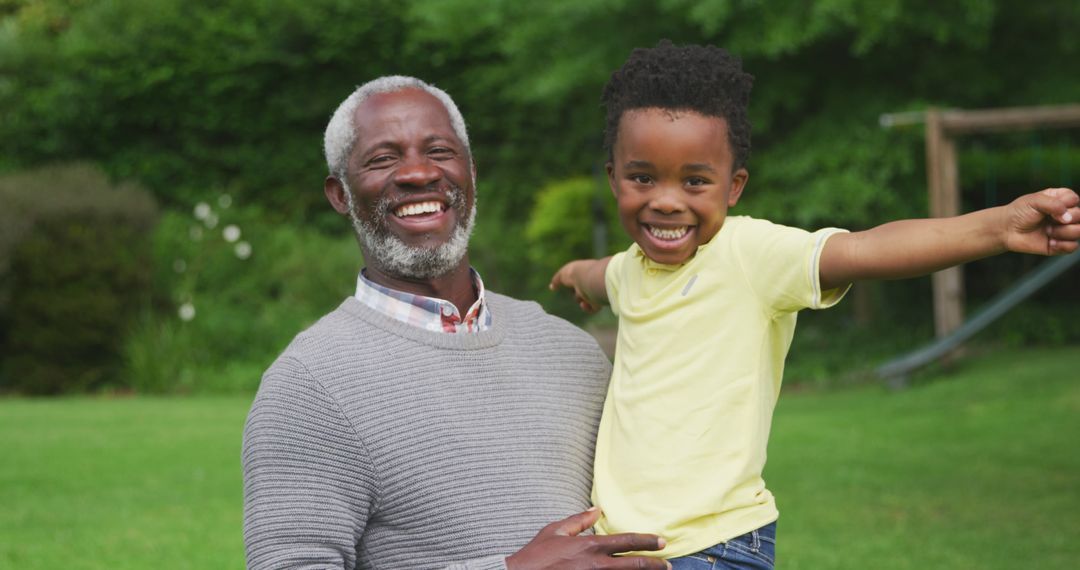 Grandfather Smiling Holding Grandson Outside Enjoying Day - Free Images, Stock Photos and Pictures on Pikwizard.com