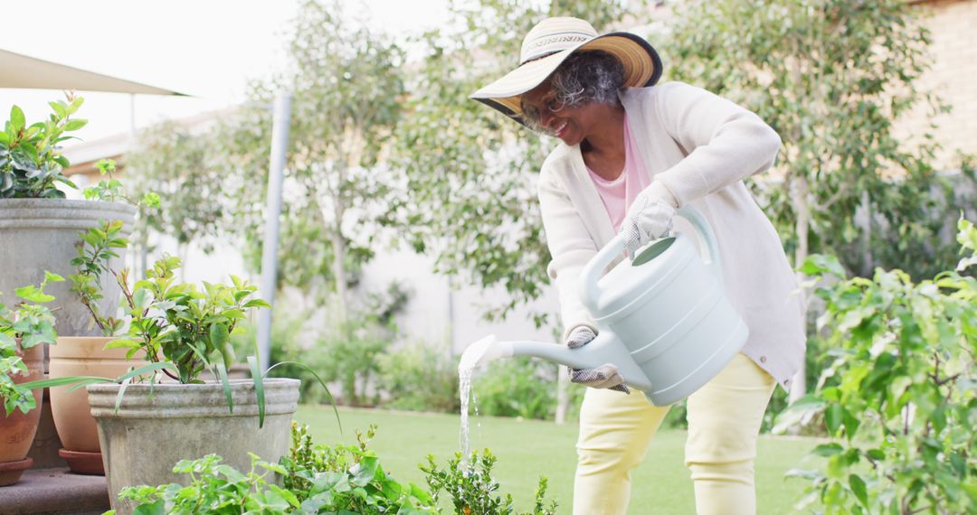 Senior woman watering plants in green garden on sunny day - Free Images, Stock Photos and Pictures on Pikwizard.com