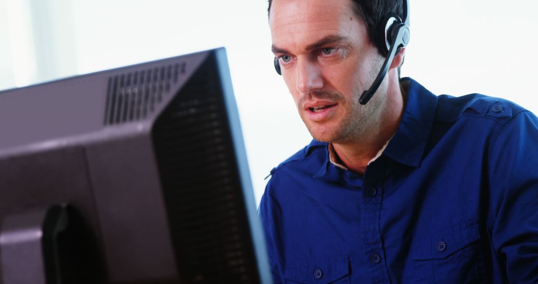 Focused Customer Service Professional with Headset at Computer