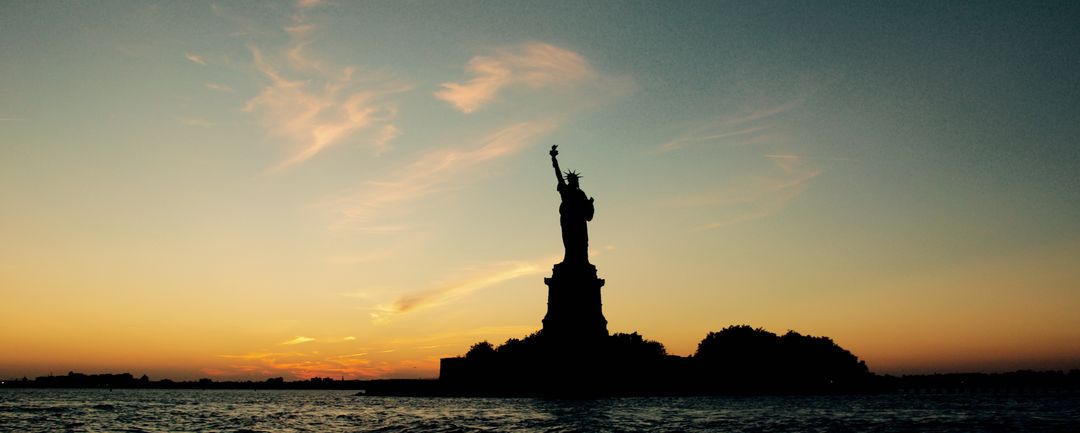 Silhouette of Statue of Liberty at Sunset Over Calm Waters - Free Images, Stock Photos and Pictures on Pikwizard.com
