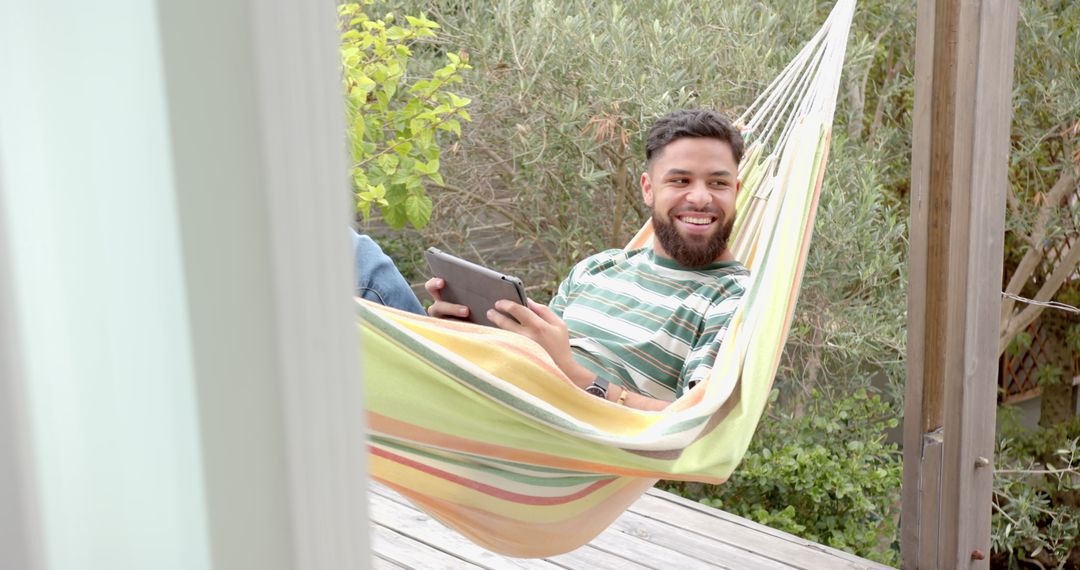 Man Relaxing Outdoors in Hammock with Digital Tablet