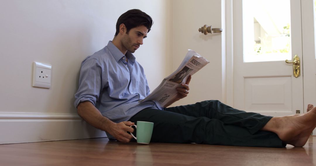 Young Man Relaxing at Home with Newspaper and Coffee Mug - Free Images, Stock Photos and Pictures on Pikwizard.com