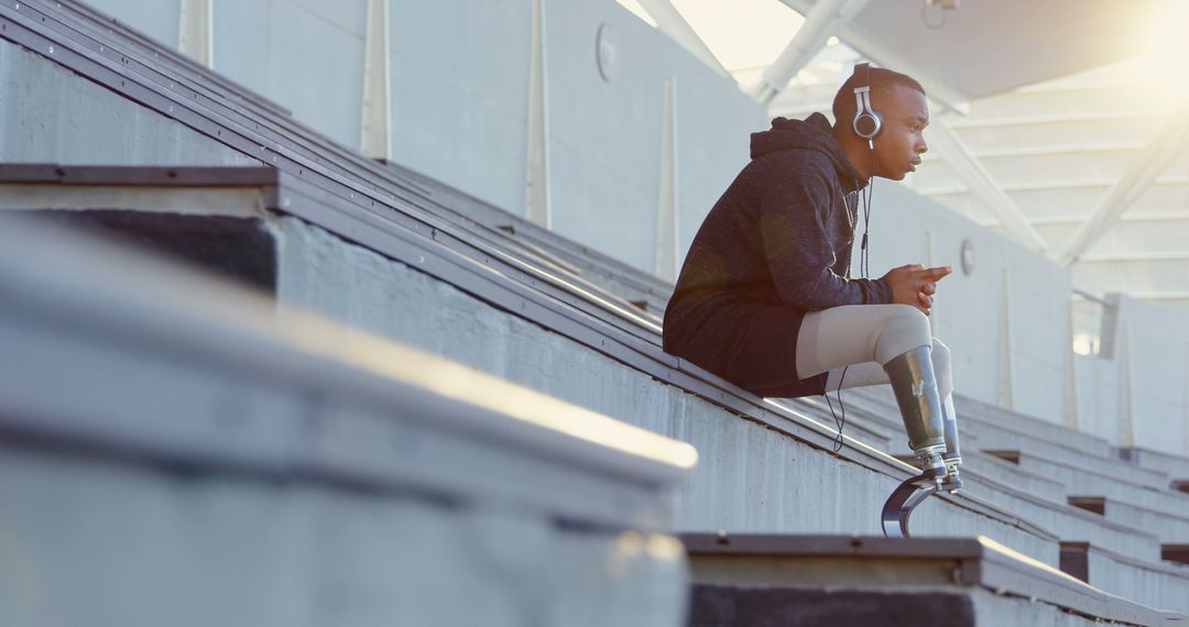 Young Athlete with Prosthetic Legs Listening to Music on Sports Bleachers - Free Images, Stock Photos and Pictures on Pikwizard.com