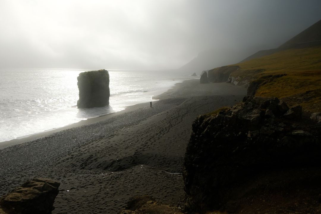 Misty Black Sand Beach with Towering Sea Stack and Lone Walker Embracing Solitude