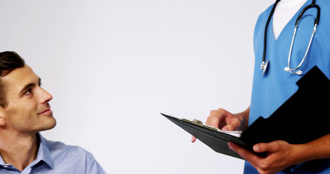 Male Patient Consulting With Doctor Reviewing Clipboard - Free Images, Stock Photos and Pictures on Pikwizard.com