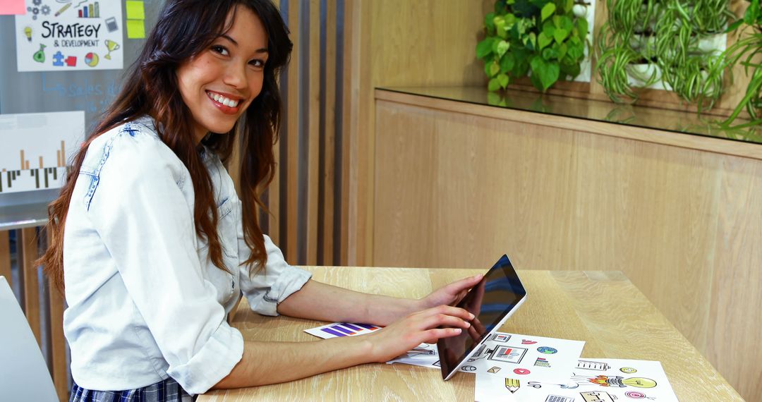 Young Woman Working on Tablet in Modern Office with Marketing Charts - Free Images, Stock Photos and Pictures on Pikwizard.com