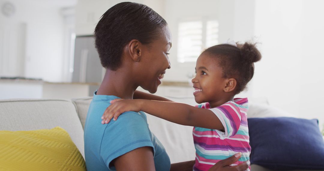 Joyful Mom and Daughter Embracing at Home on Sofa
