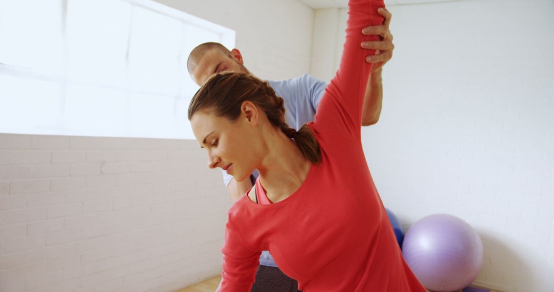 Personal trainer assisting woman with stretching exercise in fitness studio - Free Images, Stock Photos and Pictures on Pikwizard.com