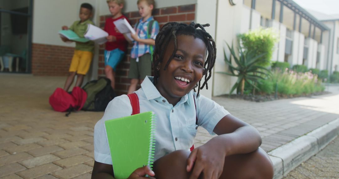 Smiling African American Boy Holding Notebook at School Campus