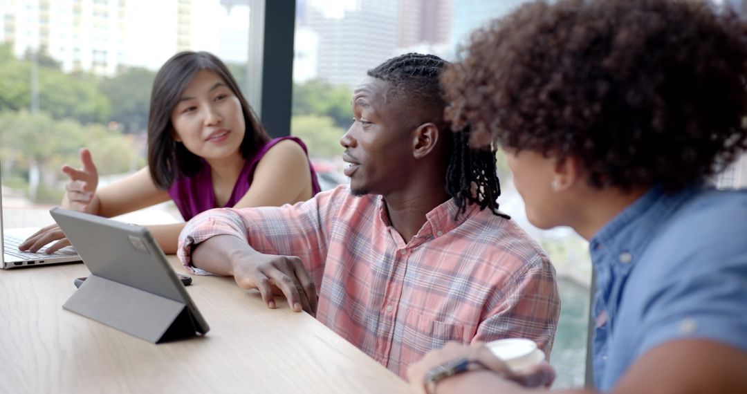 Diverse Team Collaborating Using Digital Devices in Office Workspace