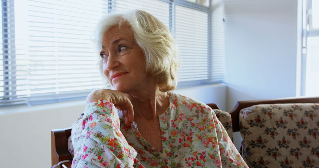 Senior Woman Relaxing and Reflecting by Window in Nursing Home