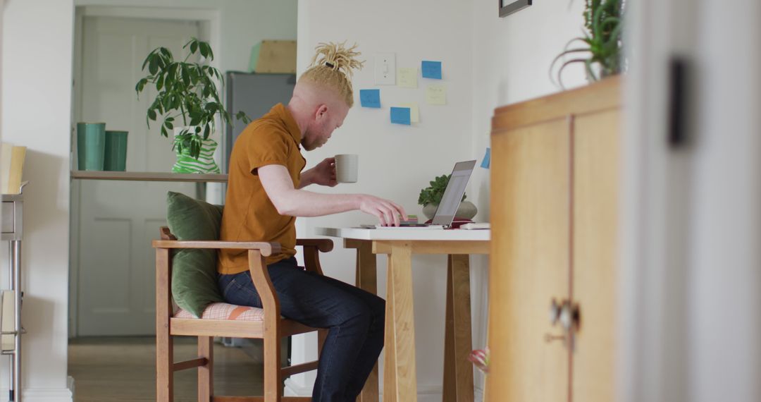 Man Working Remotely from Cozy Home Office with Laptop and Coffee - Free Images, Stock Photos and Pictures on Pikwizard.com