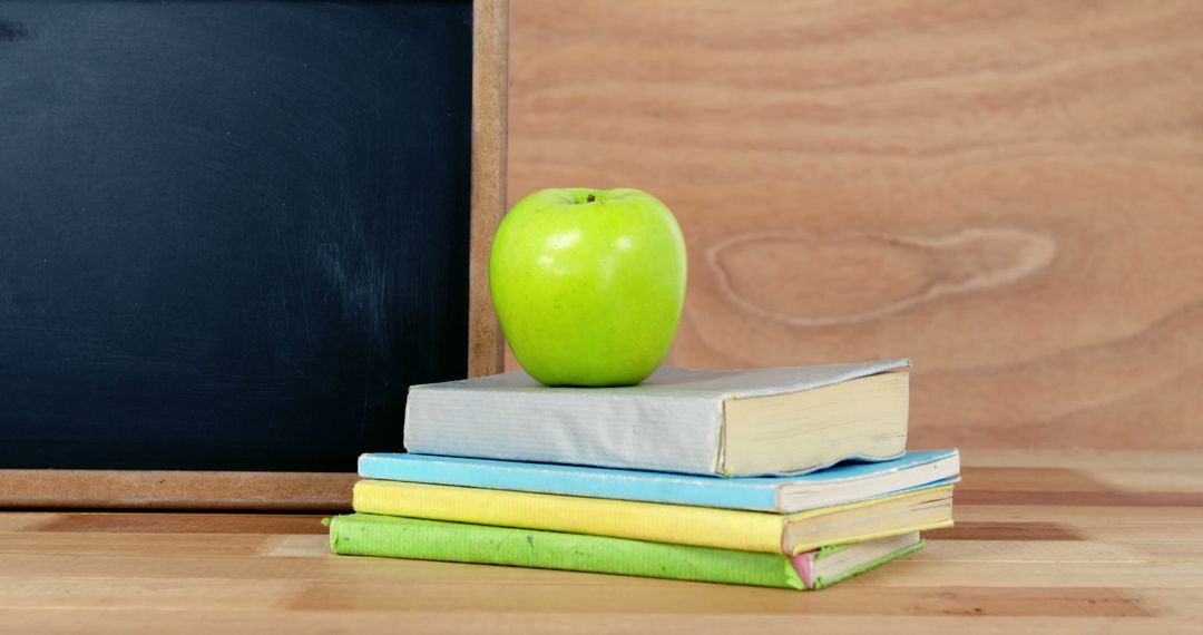 Green Apple on Stack of Books with Blackboard Background - Free Images, Stock Photos and Pictures on Pikwizard.com