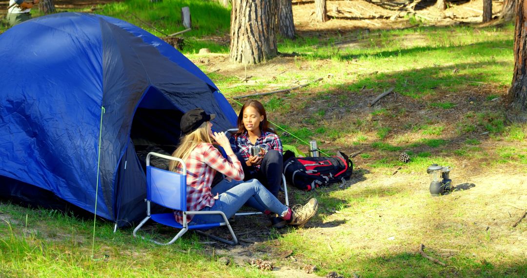 Female Hikers Relaxing by Tent in Sunny Forest Setting - Free Images, Stock Photos and Pictures on Pikwizard.com