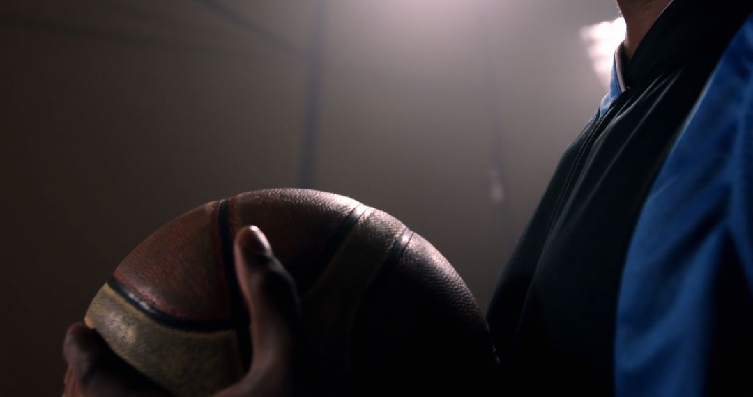 Close-Up of Athlete Holding Basketball in Dim Light