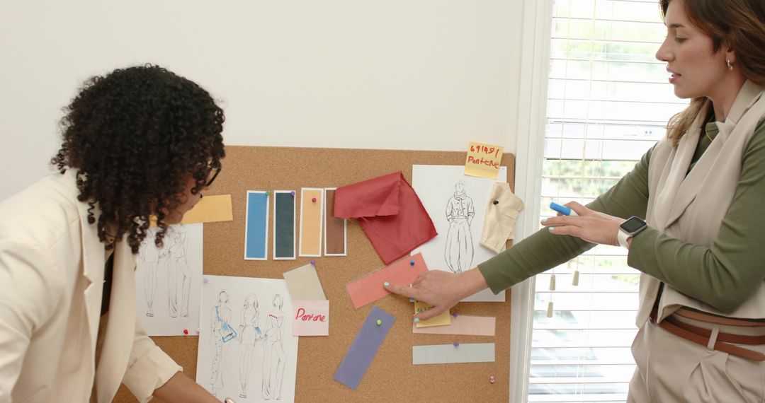 Fashion Designers Reviewing Sketches and Fabric Swatches on Corkboard