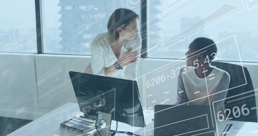 Collaborating Businesswomen Analyzing Data on Monitors in Modern Office