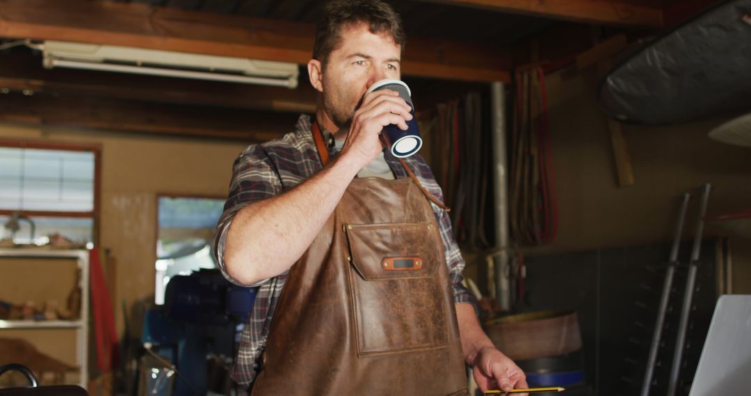 Carpenter Drinking Coffee in Workshop Wearing Leather Apron - Free Images, Stock Photos and Pictures on Pikwizard.com