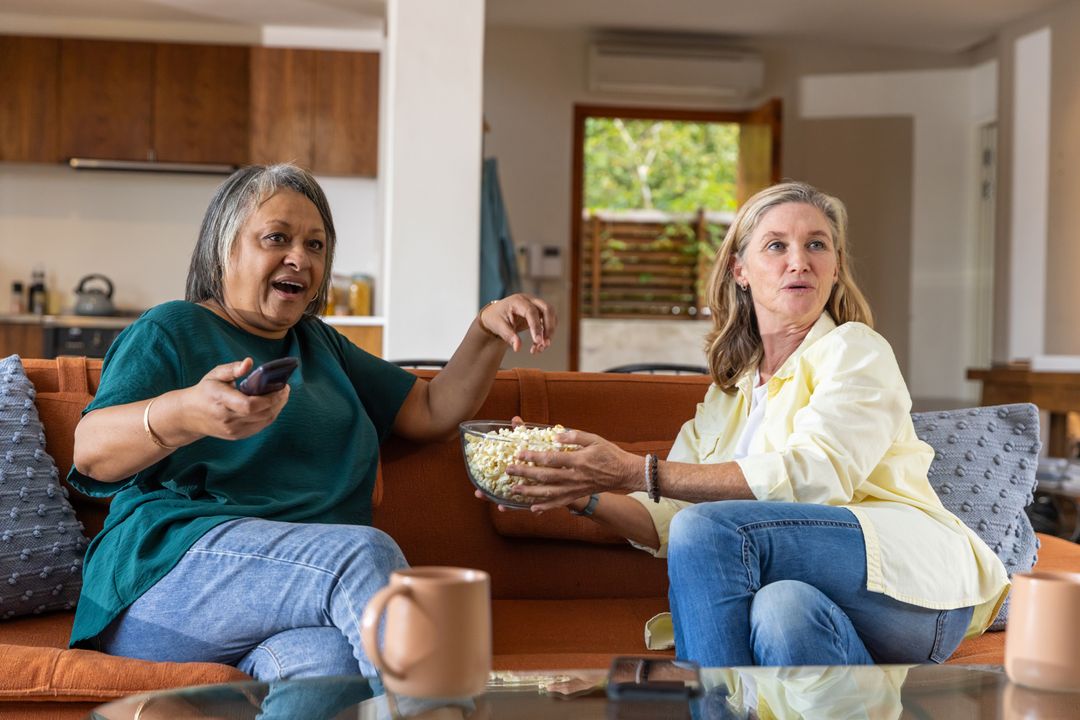 Senior Friends Sharing Popcorn during Relaxed Movie Time at Home