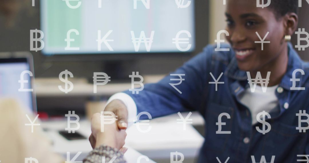 Smiling woman shaking hands across desk with currency symbols overlay for fintech