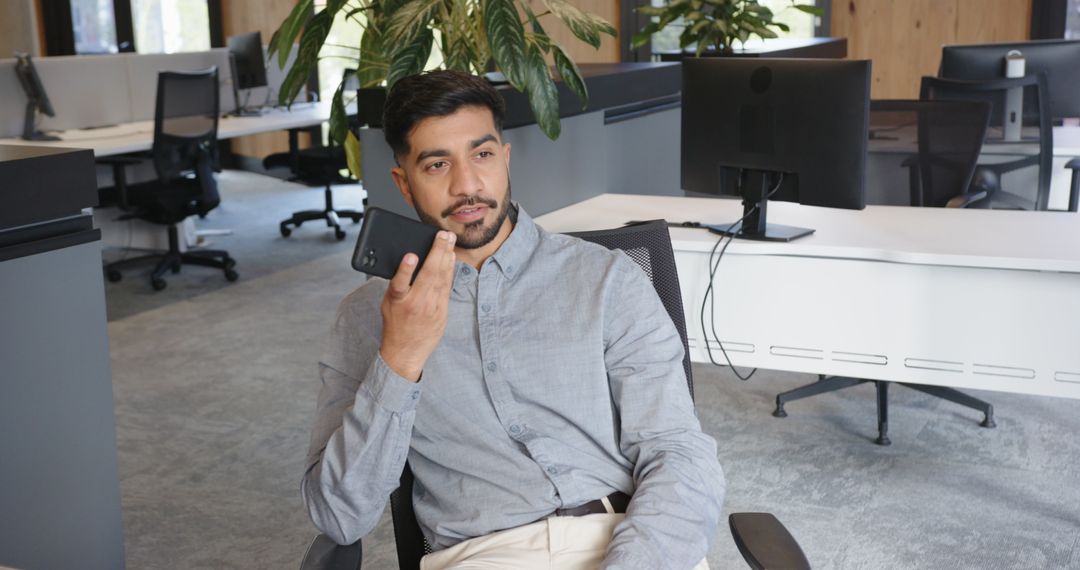 Professional Man Using Smartphone in Modern Open Office Environment