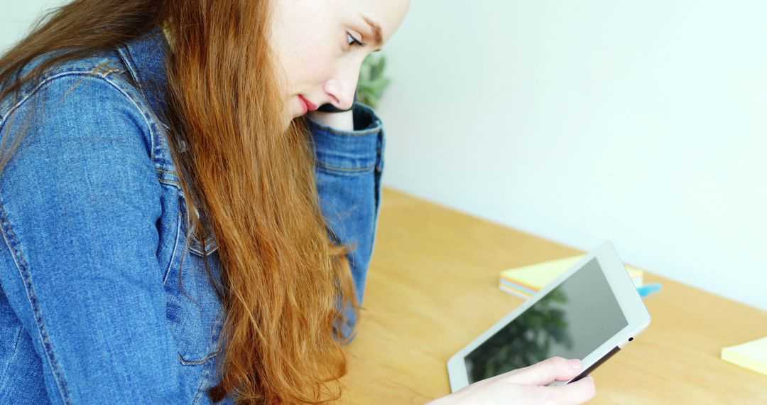 Young Woman in Denim Jacket Using Tablet for Study at Wooden Table - Free Images, Stock Photos and Pictures on Pikwizard.com