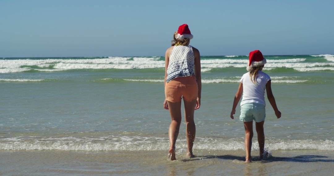 Mother and Daughter Enjoying Christmas Day at the Beach Wearing Santa Hats - Free Images, Stock Photos and Pictures on Pikwizard.com