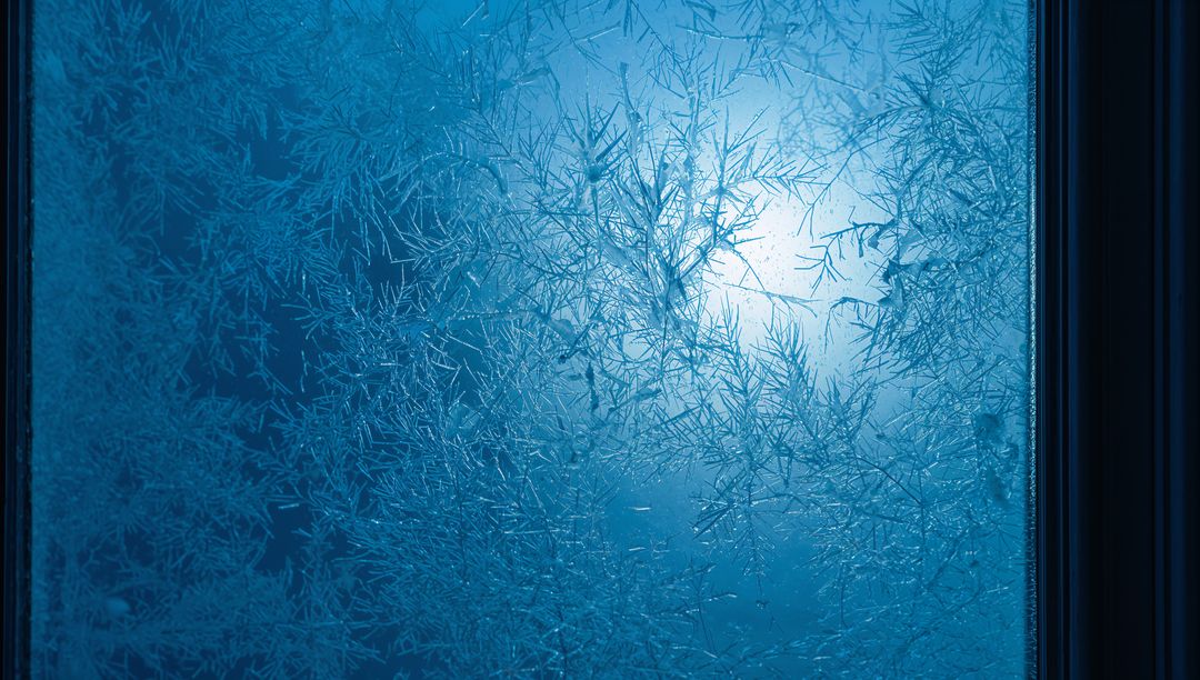 Frosted window panel revealing intricate ice crystal patterns with blue backlight glow