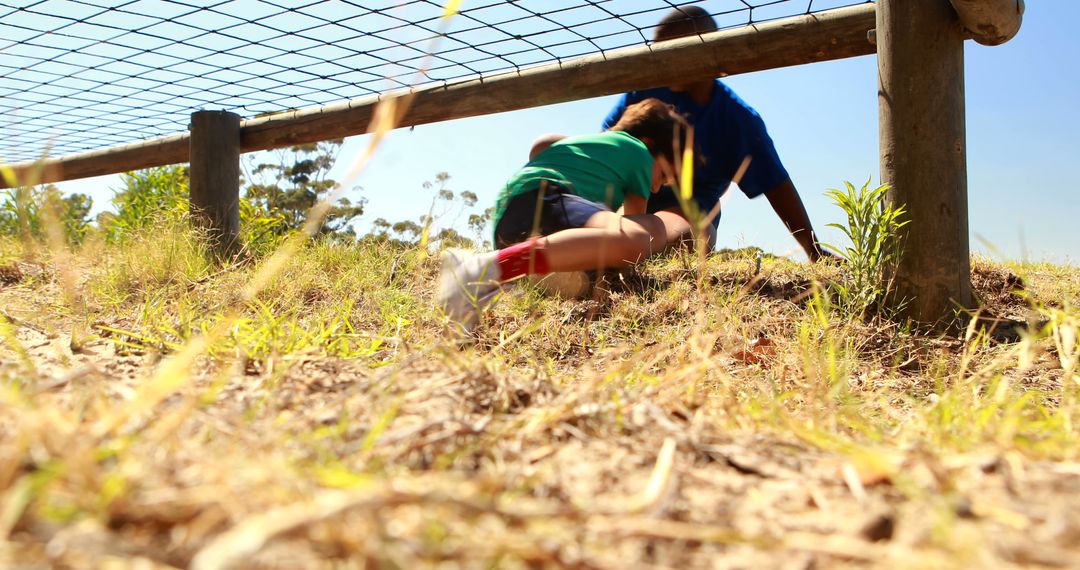 Two Kids Crawling Under Fence at Outdoor Obstacle Course - Free Images, Stock Photos and Pictures on Pikwizard.com