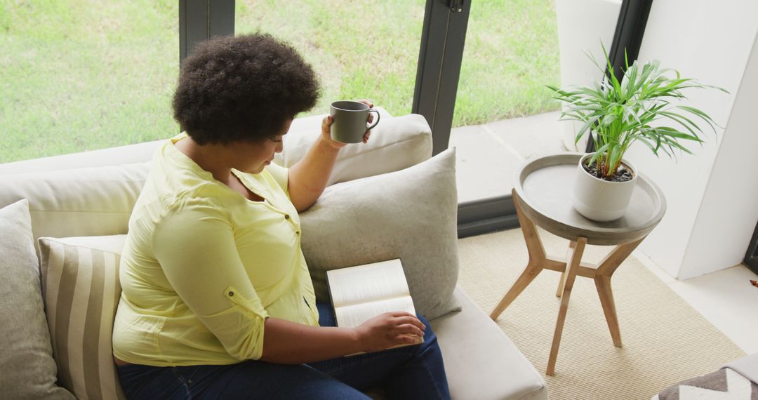 Woman Relaxing on Sofa with Book and Coffee - Free Images, Stock Photos and Pictures on Pikwizard.com