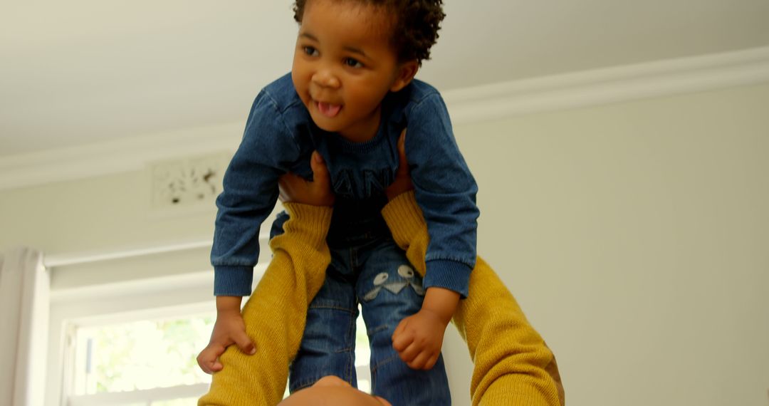 Parent lifting smiling toddler in playful moment indoors - Free Images, Stock Photos and Pictures on Pikwizard.com