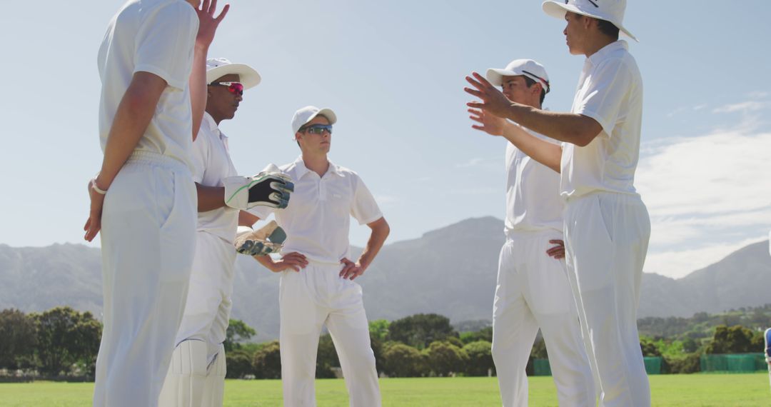 Cricket Team Huddling During Match with Mountains in Background - Free Images, Stock Photos and Pictures on Pikwizard.com