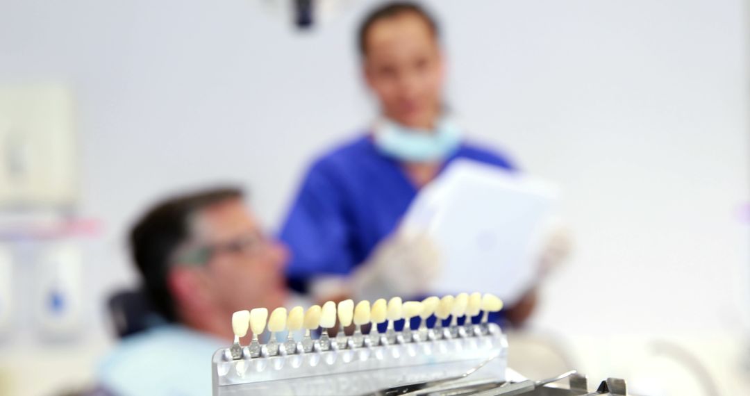 Dental Professional Adjusting Tooth Shade Chart with Patient in Background - Free Images, Stock Photos and Pictures on Pikwizard.com