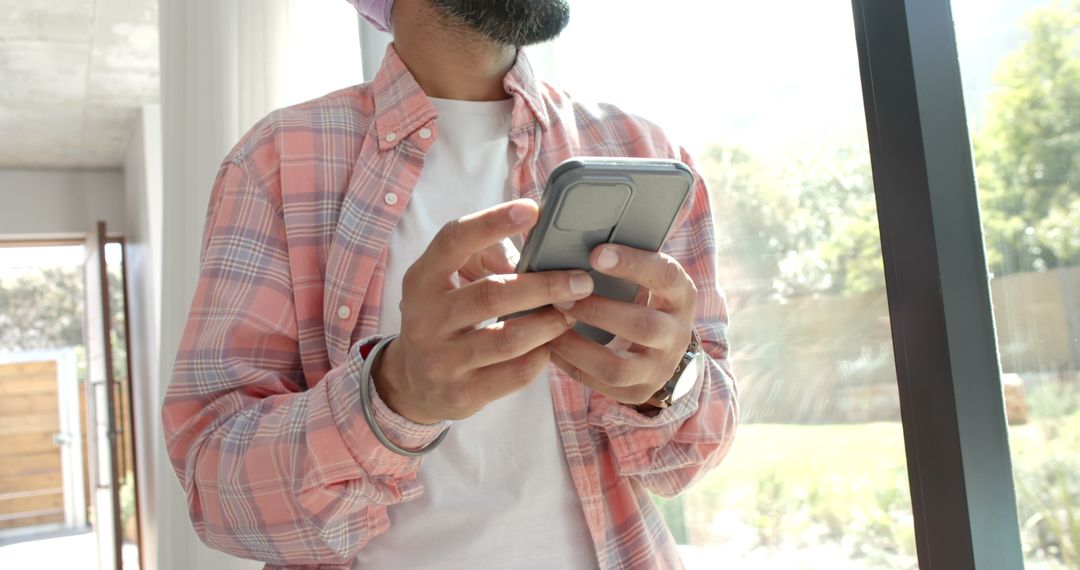 Man with Smartphone Enjoying Leisure Time by Window