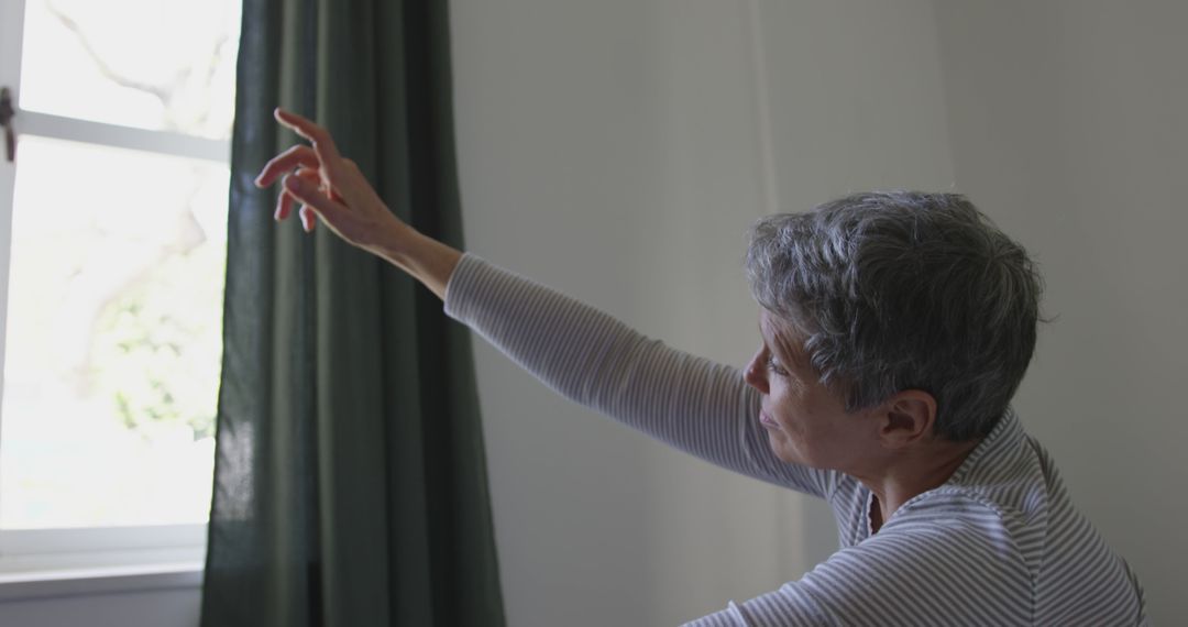 Senior Woman Stretching Arm Towards Window - Free Images, Stock Photos and Pictures on Pikwizard.com