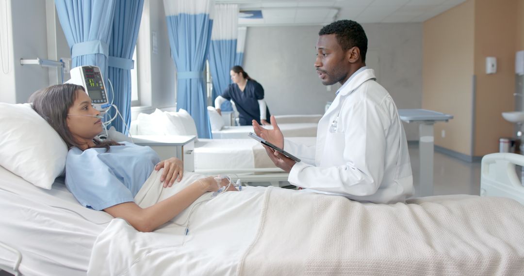 Doctor Consulting Patient in Hospital Room Using Tablet