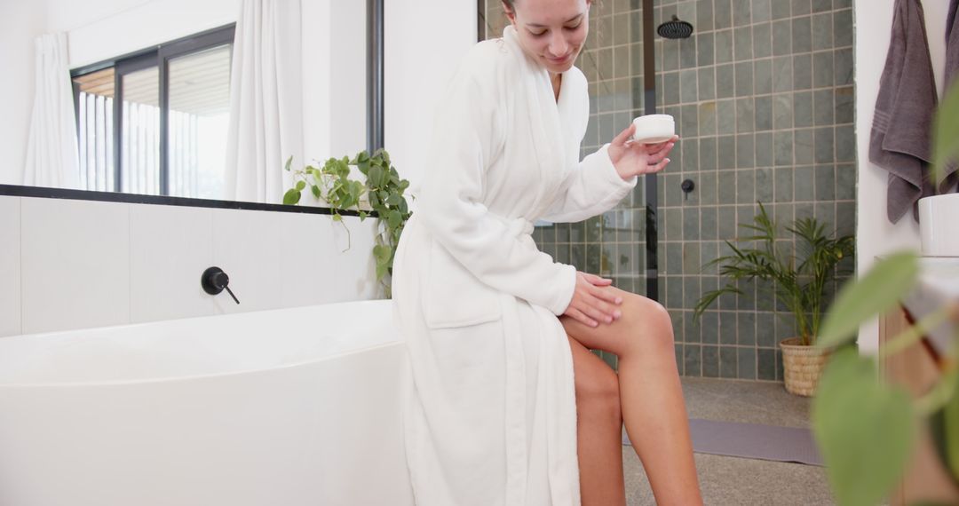 Woman in Bathrobe Using Lotion in Modern Minimalist Bathroom
