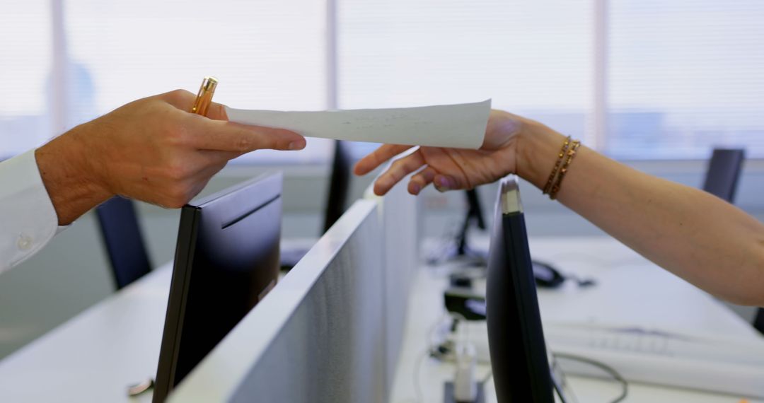 Colleagues Exchanging Documents Over Office Cubicle Partition
