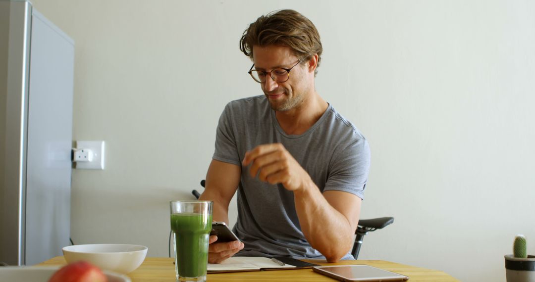 Man Enjoying Green Smoothie While Using Phone at Home - Free Images, Stock Photos and Pictures on Pikwizard.com