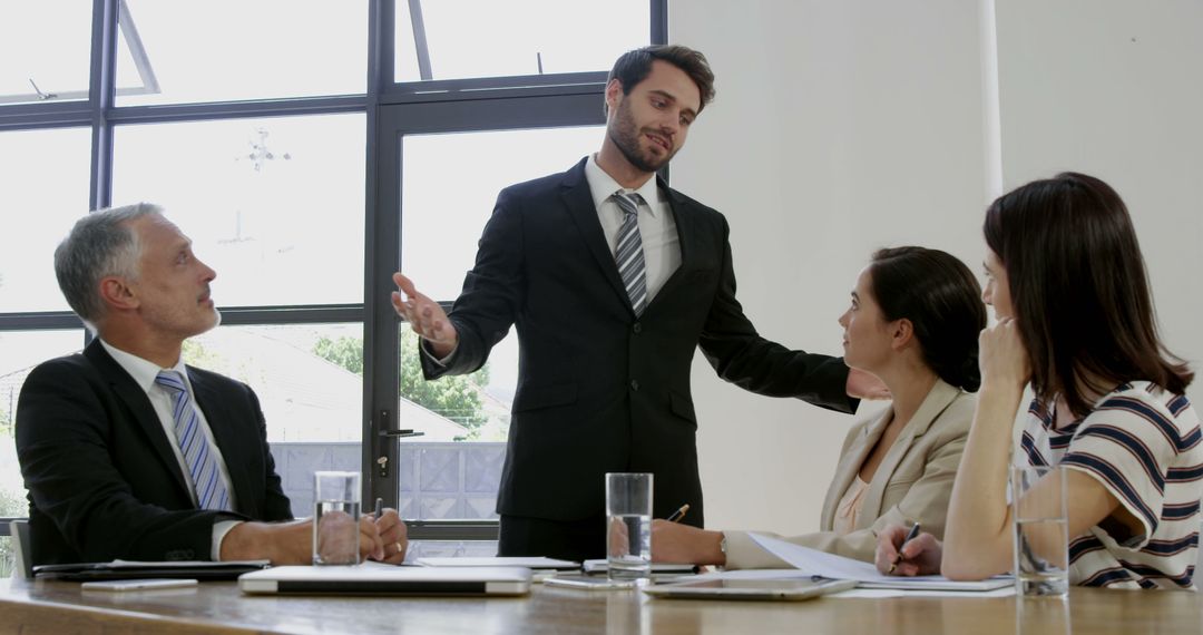 Confident Businessman Presenting to Colleagues in Modern Office