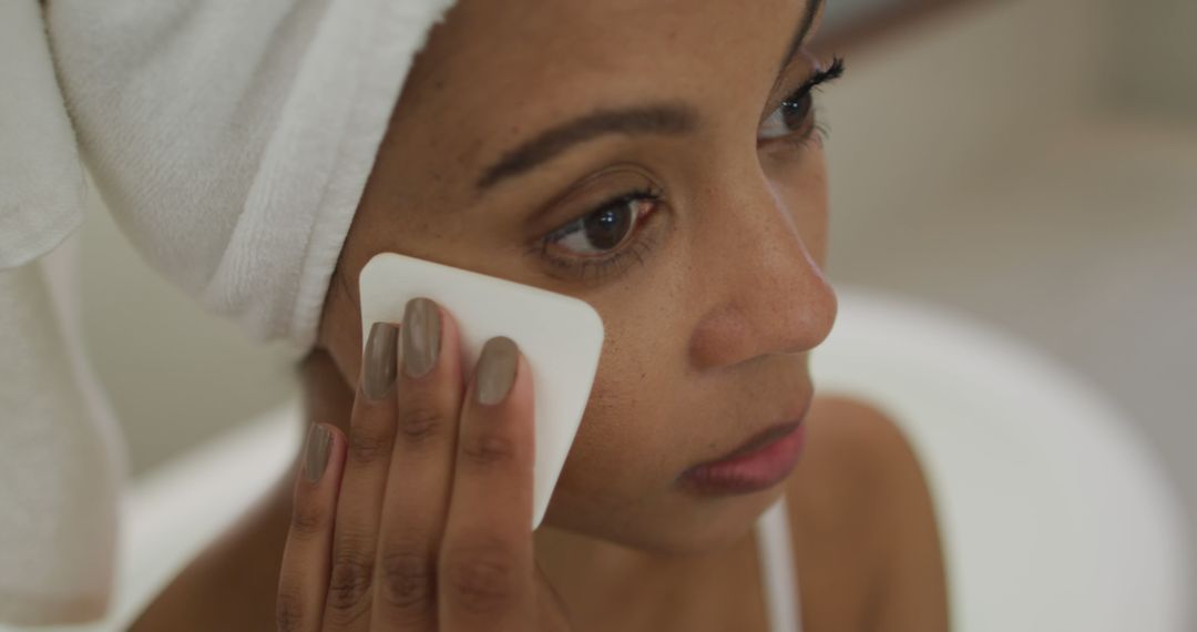 Biracial woman wearing towel on head cleaning her face - Free Images, Stock Photos and Pictures on Pikwizard.com