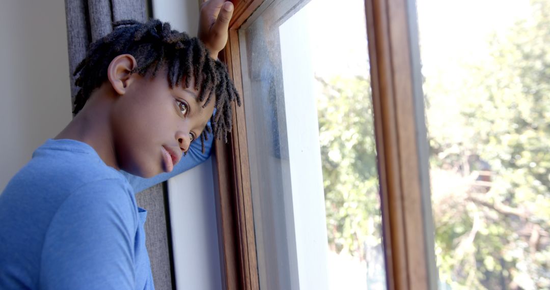 Pensive Boy Looking Out Window on Sunny Day - Free Images, Stock Photos and Pictures on Pikwizard.com