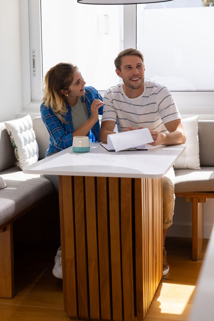 Couple Relaxing in Sunlit Home Reviewing Documents