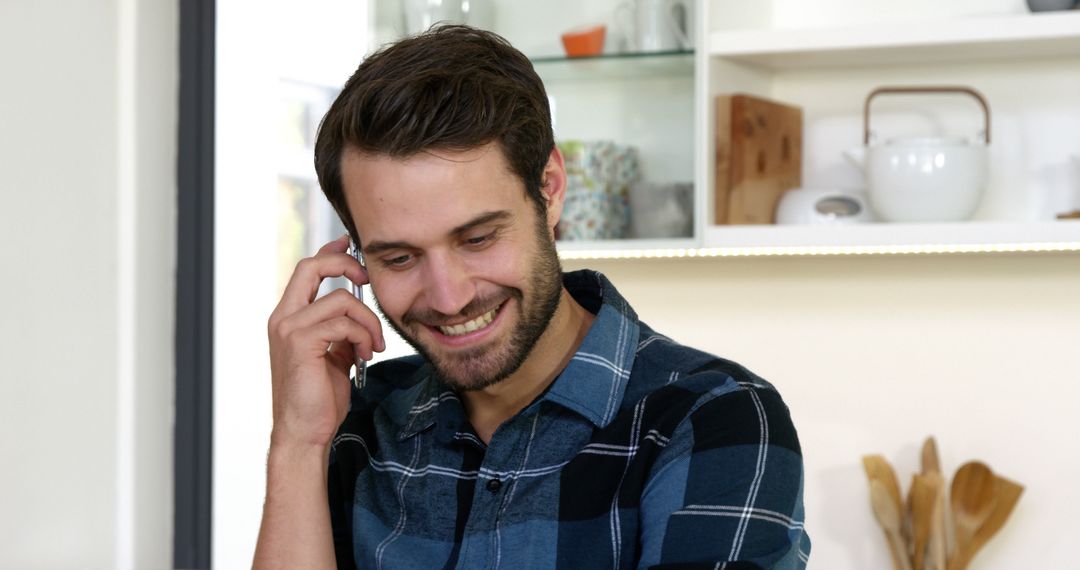 Smiling Man Talking on Mobile Phone in Kitchen - Free Images, Stock Photos and Pictures on Pikwizard.com