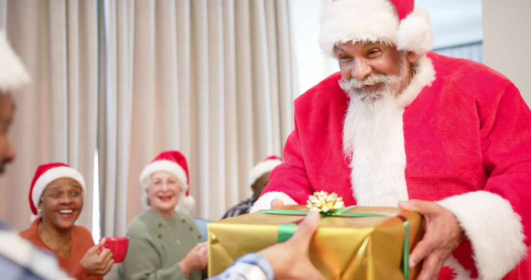 Santa Claus giving gift to people wearing Santa hats on Christmas celebration - Free Images, Stock Photos and Pictures on Pikwizard.com