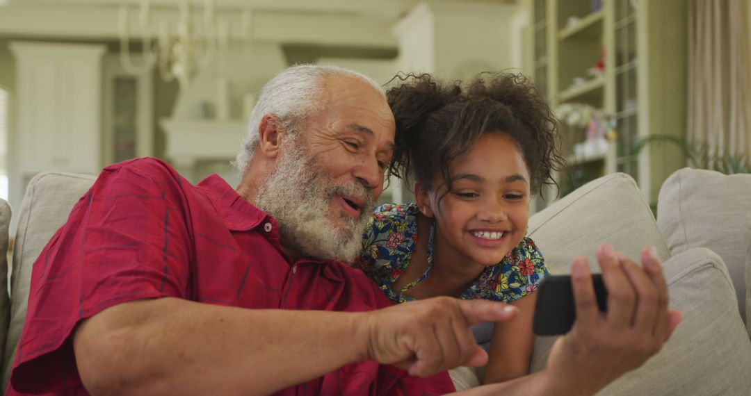 Senior Man and Smiling Granddaughter Using Smartphone Together at Home - Free Images, Stock Photos and Pictures on Pikwizard.com