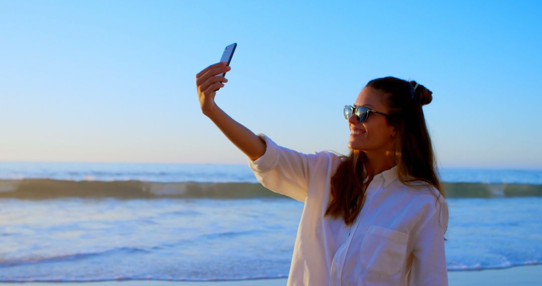 Smiling Woman Taking Selfie at Beach During Sunset - Free Images, Stock Photos and Pictures on Pikwizard.com