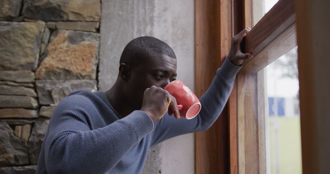 Man Sipping Hot Beverage While Looking Out Window - Free Images, Stock Photos and Pictures on Pikwizard.com