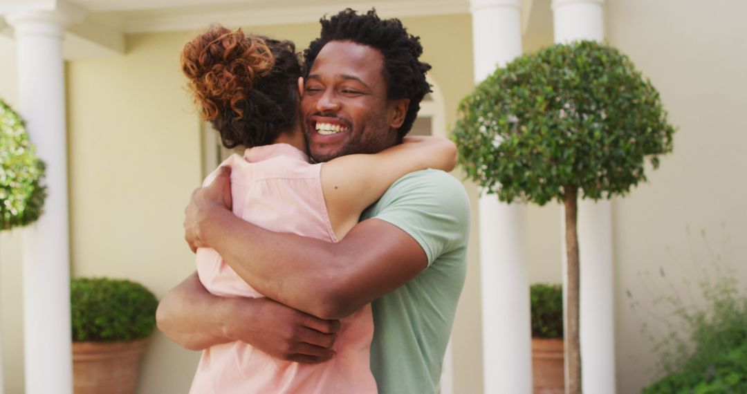 Biracial Couple Embracing in Front of New Home